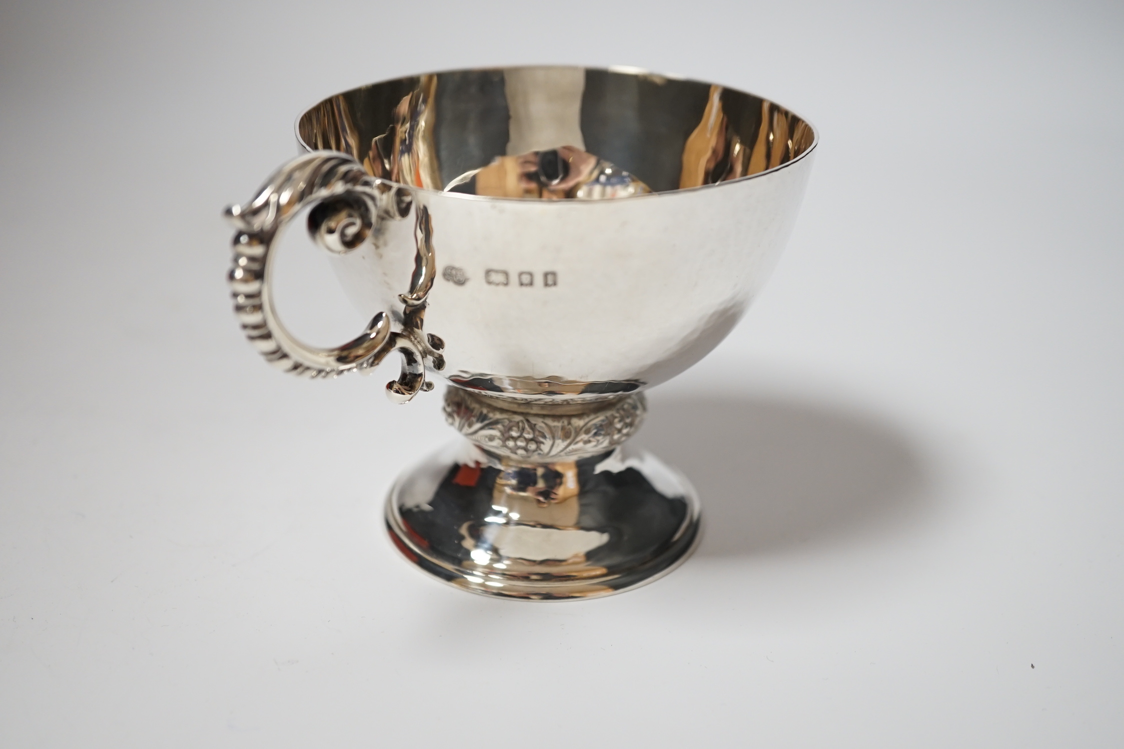 A George V planished silver pedestal single handled cup, Goldsmiths & Silversmiths Co Ltd, London, 1926, 86mm, 5.9oz.
